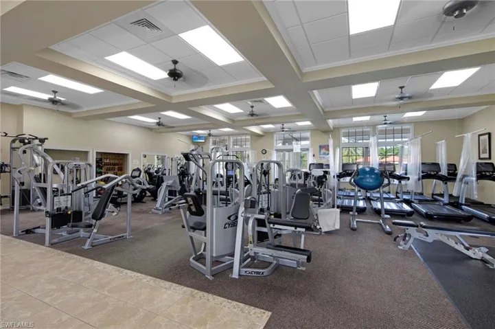 Fitness center featuring a variety of exercise equipment, recessed lighting, ceiling fans, large windows, and a combination of carpet and tile flooring