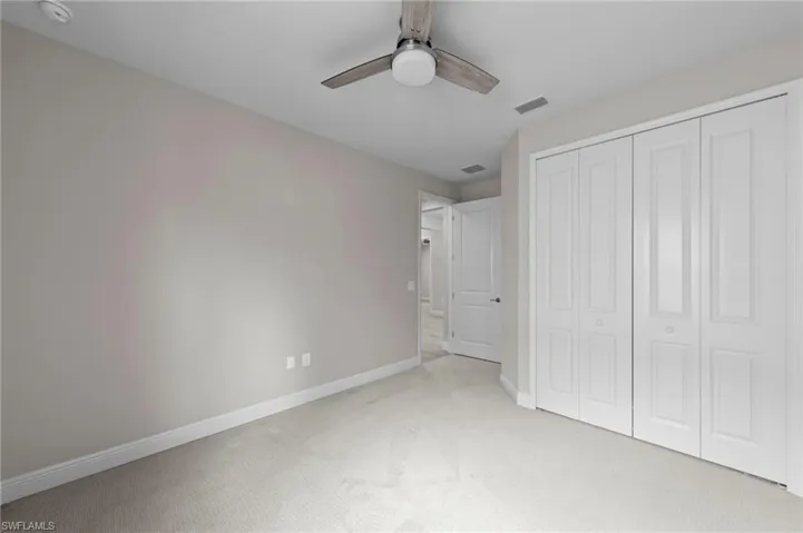 Carpeted room with neutral walls, white baseboards, and a contemporary ceiling fan