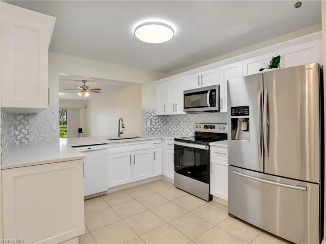 Kitchen featuring backsplash, stainless steel appliances, white cabinetry, and sink