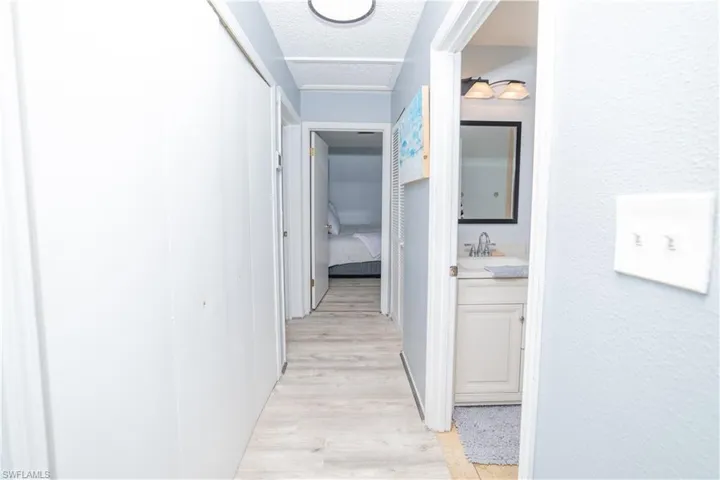 Corridor featuring sink, a textured ceiling, and light wood-type flooring