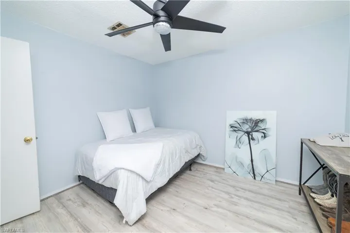 Bedroom with ceiling fan, light hardwood / wood-style floors, and a textured ceiling