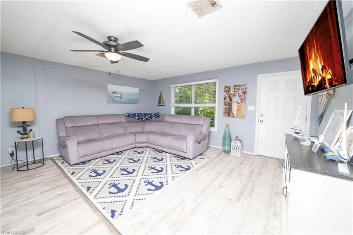 Living room with a textured ceiling, light hardwood / wood-style flooring, and ceiling fan