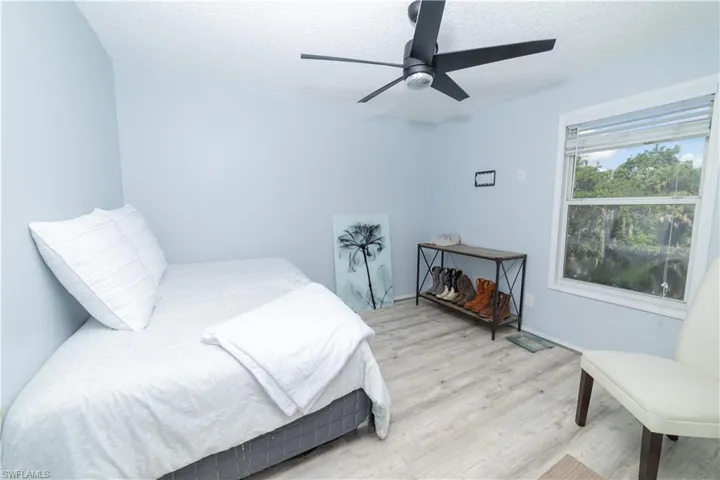 Bedroom featuring ceiling fan, light hardwood / wood-style flooring, and a textured ceiling