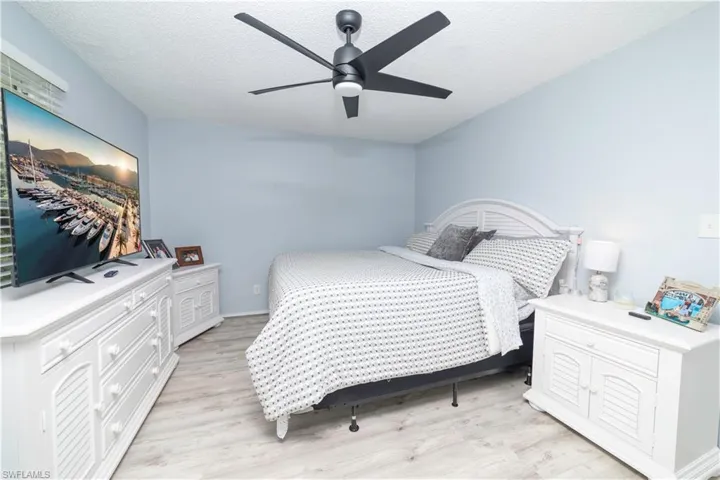 Bedroom with a textured ceiling, light hardwood / wood-style flooring, and ceiling fan