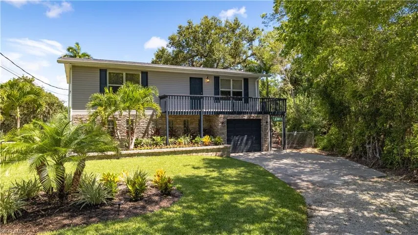 View of front of house with a balcony, a front yard, and a garage