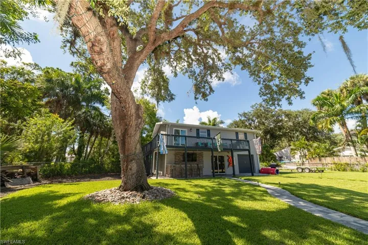 Rear view of property with a lawn, a wooden deck, and a garage