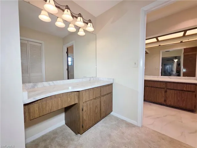 Bathroom featuring vanity, a closet, and light marble finish floors