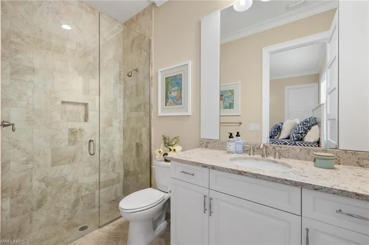 Bathroom featuring vanity, toilet, crown molding, and a shower with door