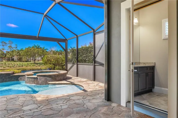View of pool with an in ground hot tub, glass enclosure, and a patio area
