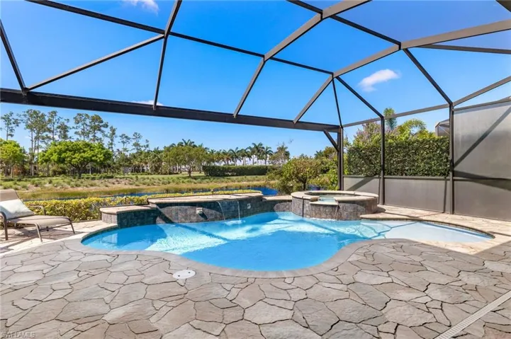 View of swimming pool with glass enclosure, an in ground hot tub, a patio area, and pool water feature