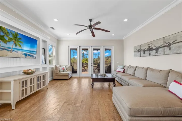 Living room upstairs featuring crown molding, french doors, light wood-type flooring, and ceiling fan but technically a bedroom w a half bath