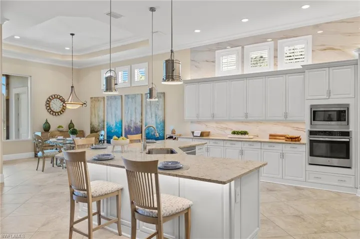 Kitchen with decorative light fixtures, appliances with stainless steel finishes, sink, and a raised ceiling