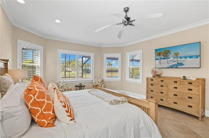 Bedroom with ceiling fan, light tile flooring, and crown molding