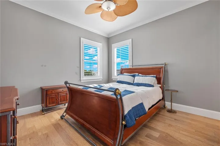 Bedroom with ceiling fan, light hardwood / wood-style floors, and ornamental molding
