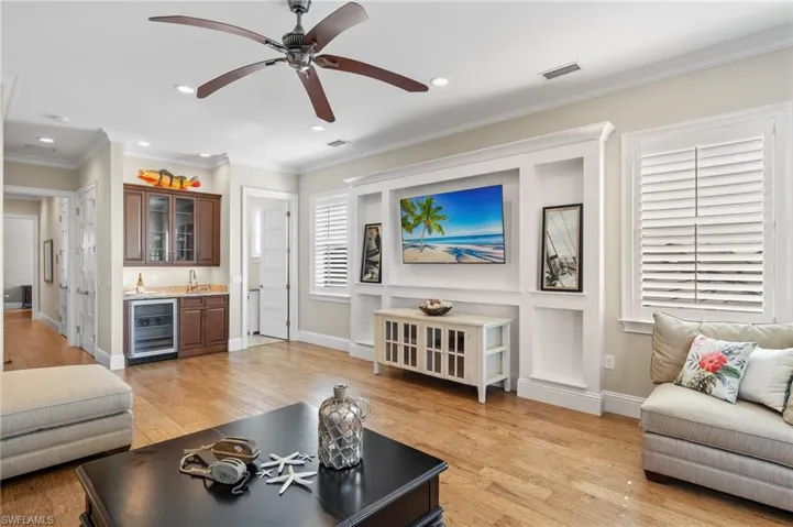 Living room upstairs with crown molding, ceiling fan, wine cooler, and light hardwood / wood-style flooring