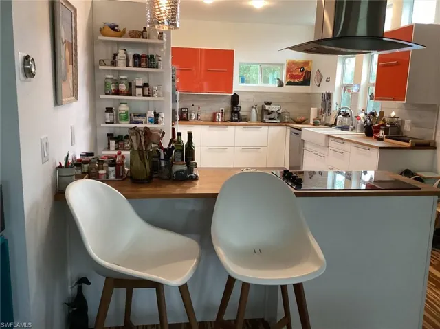 Kitchen with island range hood, white cabinets, and backsplash