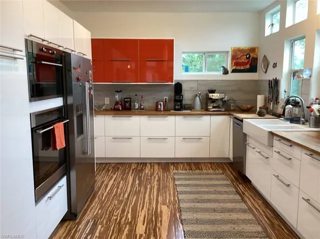 Kitchen featuring sink, appliances with stainless steel finishes, tasteful backsplash, white cabinets, and dark hardwood / wood-style flooring