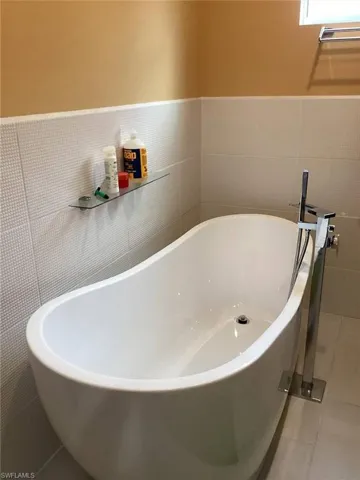 Bathroom featuring tile patterned floors, a tub to relax in, and tile walls