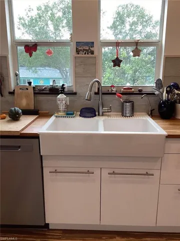 Kitchen featuring stainless steel dishwasher, sink, decorative backsplash, and white cabinets