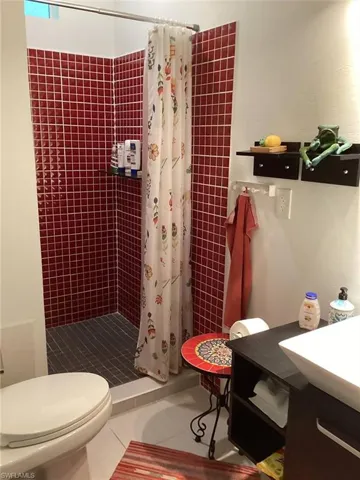 Bathroom featuring vanity, toilet, curtained shower, and tile patterned flooring