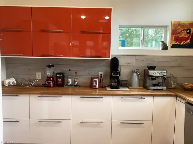 Bar featuring tasteful backsplash, stainless steel dishwasher, and butcher block countertops