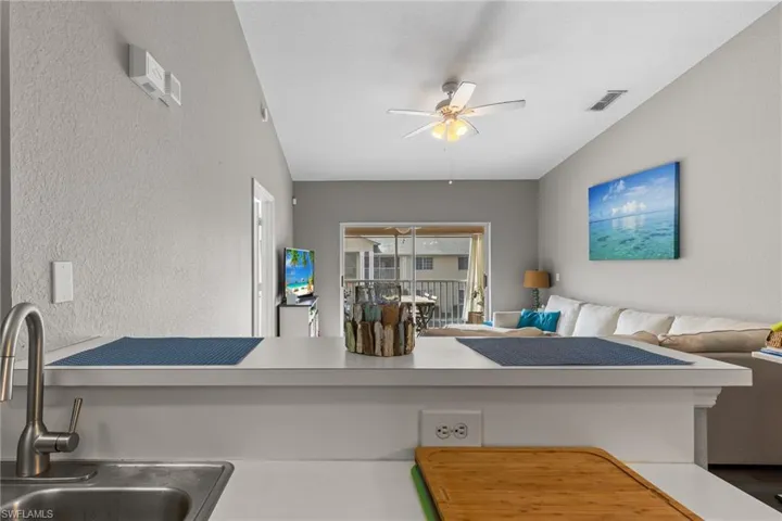 Living room featuring vaulted ceiling, ceiling fan, and sink
