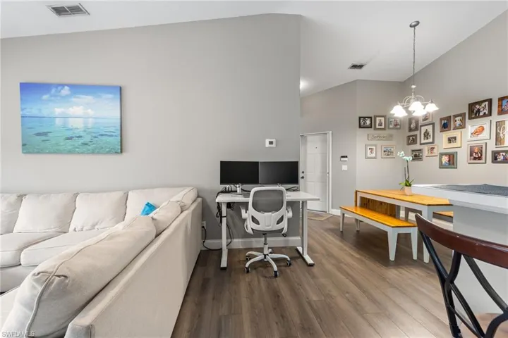 Office area with hardwood / wood-style flooring, lofted ceiling, and a chandelier