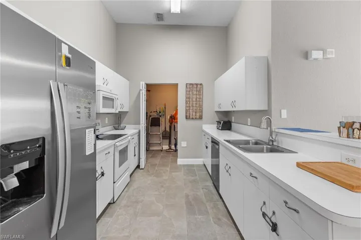 Kitchen with stainless steel appliances, sink, and white cabinets