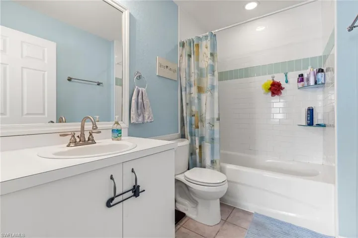Full bathroom featuring shower / bathtub combination with curtain, vanity, tile patterned floors, and toilet