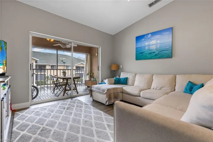 Living room with hardwood / wood-style flooring, vaulted ceiling, and ceiling fan