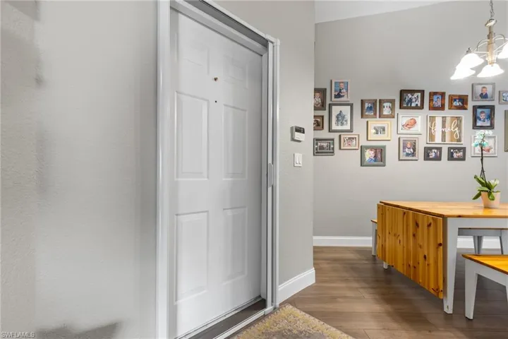 Hall with dark wood-type flooring and a notable chandelier