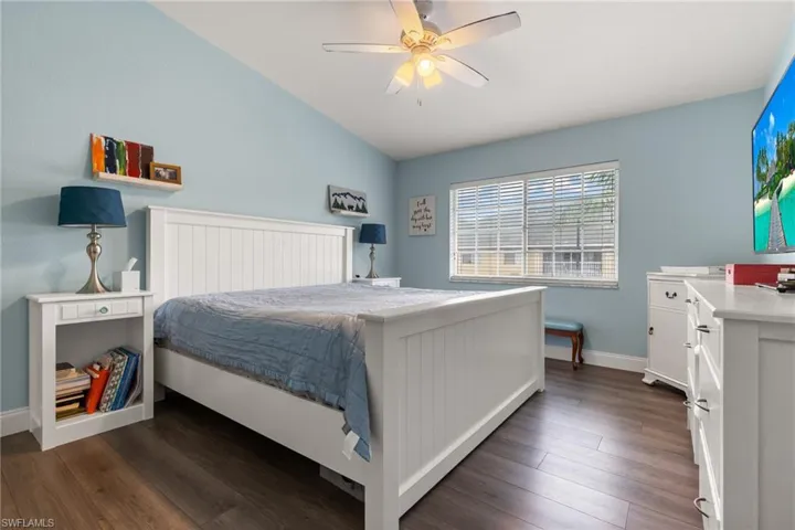 Bedroom with vaulted ceiling, dark wood-type flooring, and ceiling fan