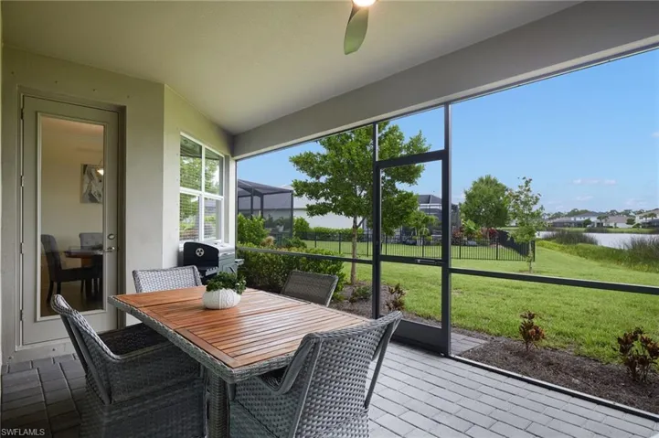 Sunroom / solarium featuring a water view, a ceiling fan, and outdoor dining area