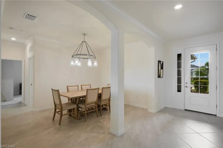 Dining room featuring ornamental molding, a chandelier, arched walkways, light tile patterned floors, and recessed lighting