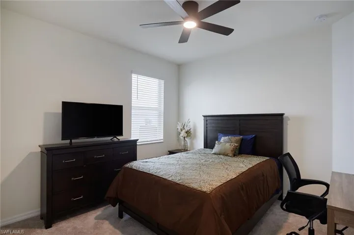 Bedroom with light carpet and a ceiling fan