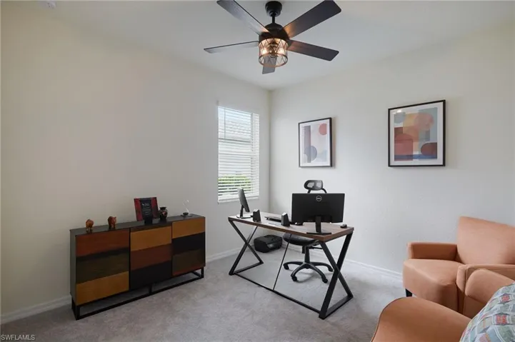 Home office featuring light carpet and a ceiling fan