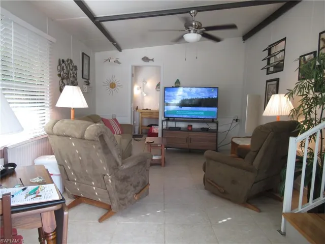 Living area with ceiling fan, tile patterned floors, and radiator