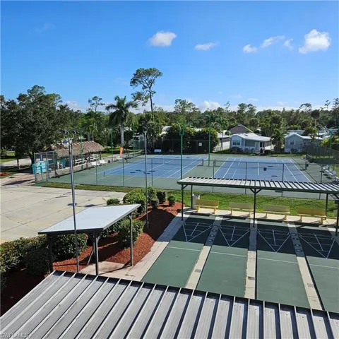 View of tennis court featuring shuffleboard and view of scattered trees