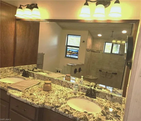 Full bath featuring double vanity and tiled shower