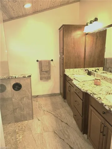 Full bath featuring wood ceiling, walk in shower, double vanity, marble finish flooring, and recessed lighting