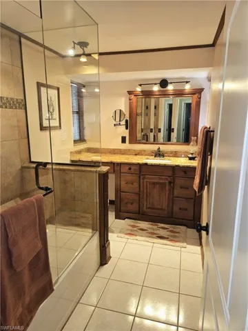 Bathroom featuring tile patterned flooring, vanity, a shower with shower door, a tub, and ornamental molding