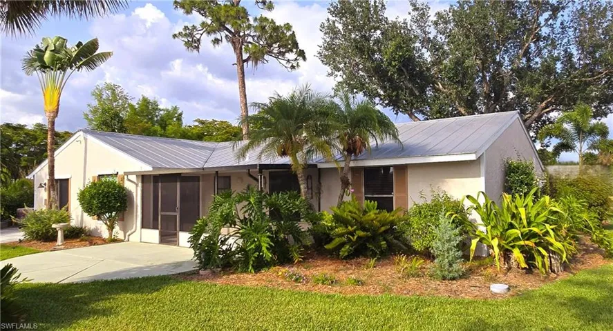 Single story home with stucco siding, a front yard, and a metal roof