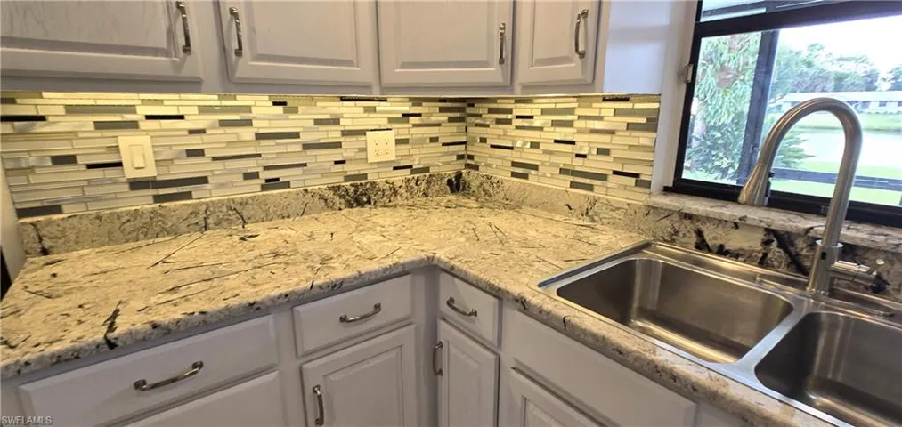 Kitchen featuring backsplash, gray cabinets, and light stone counters
