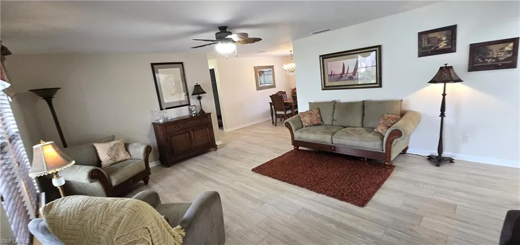 Living area featuring a ceiling fan, light wood-style floors, and a chandelier