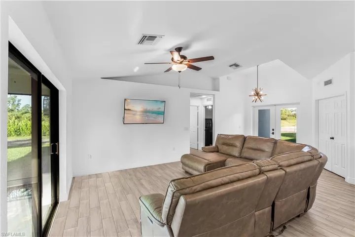 Living room featuring ceiling fan, lofted ceiling, light wood-type flooring, and french doors