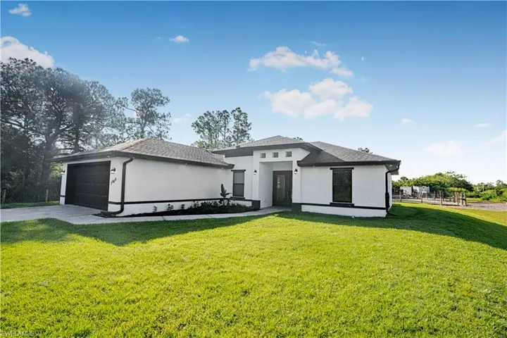 View of front facade featuring a garage and a front lawn
