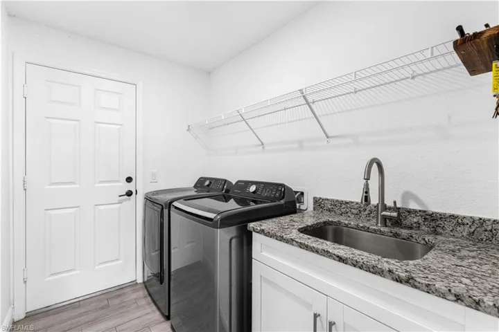 Laundry room featuring light hardwood / wood-style flooring, washing machine and clothes dryer, cabinets, and sink