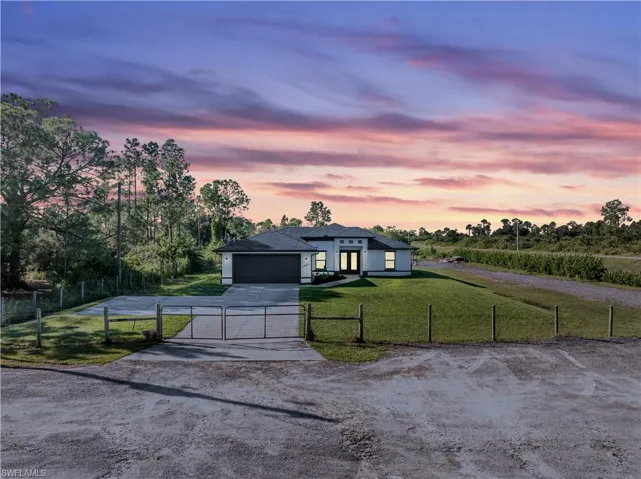 View of front of property with a garage and a yard