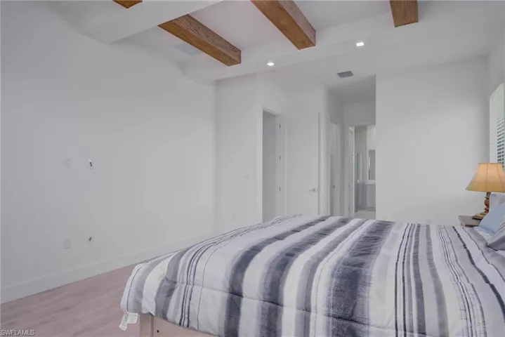 Bedroom featuring beam ceiling, light wood-type flooring, and recessed lighting