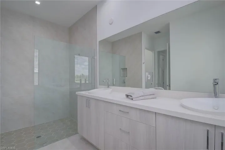 Full bath featuring double vanity, walk in shower, and tile patterned floors